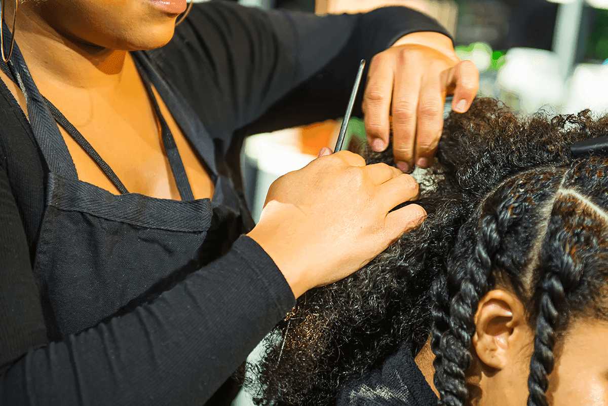 Stylist guiding hair into a braiding tool